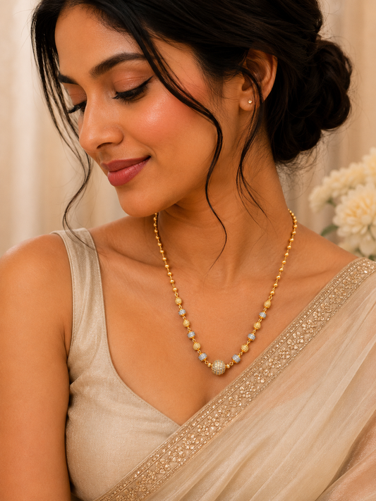 17-inch gold-plated Mug Mala necklace with gold and silver-tone beads and a CZ-studded center bead on a black jewelry bust. The Mirage Fashion