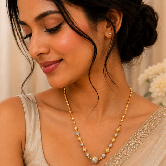 17-inch gold-plated Mug Mala necklace with gold and silver-tone beads and a CZ-studded center bead on a black jewelry bust. The Mirage Fashion
