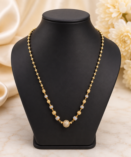 17-inch gold-plated Mug Mala necklace with gold and silver-tone beads and a CZ-studded center bead on a black jewelry bust.  The Mirage Fashion