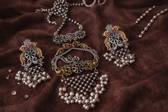 Ornate jewelry set with pendants and beads on a brown fabric background