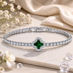 Silver bracelet with a green gemstone on a light fabric background with flowers.