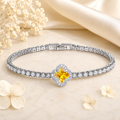 Silver bracelet with a yellow gemstone on a beige background with flowers
