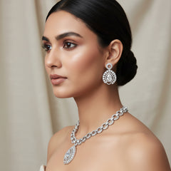 Silver necklace with decorative pendants on a textured beige surface