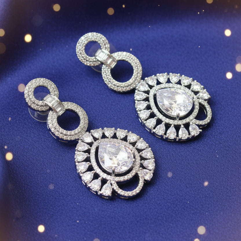 Pair of silver earrings with gemstones on a textured fabric background