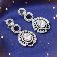 Pair of silver earrings with gemstones on a textured fabric background