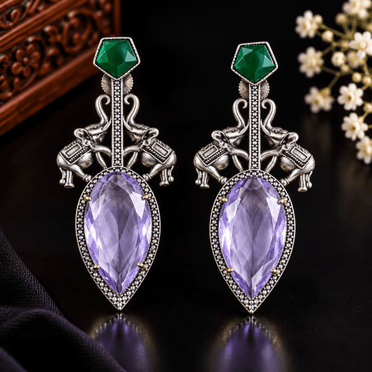 Oxidized silver-tone statement earrings with elephant motifs, lavender-purple faceted stones and emerald-green accents