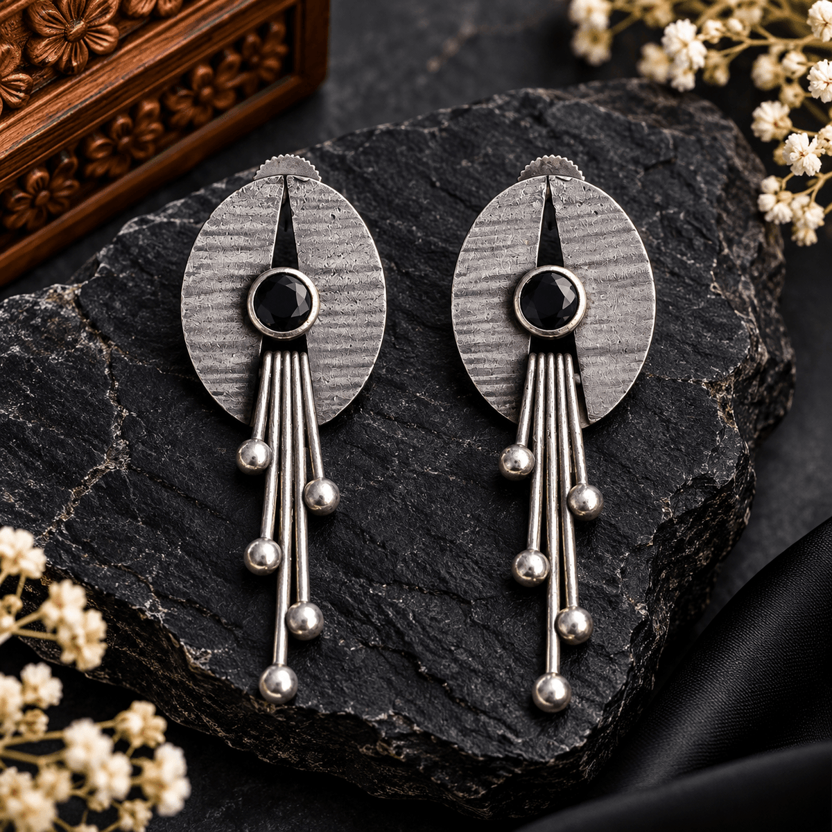 Antique oxidized silver oval earrings with round black stones and long metallic rods ending in spherical beads