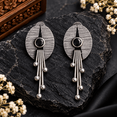 Antique oxidized silver oval earrings with round black stones and long metallic rods ending in spherical beads