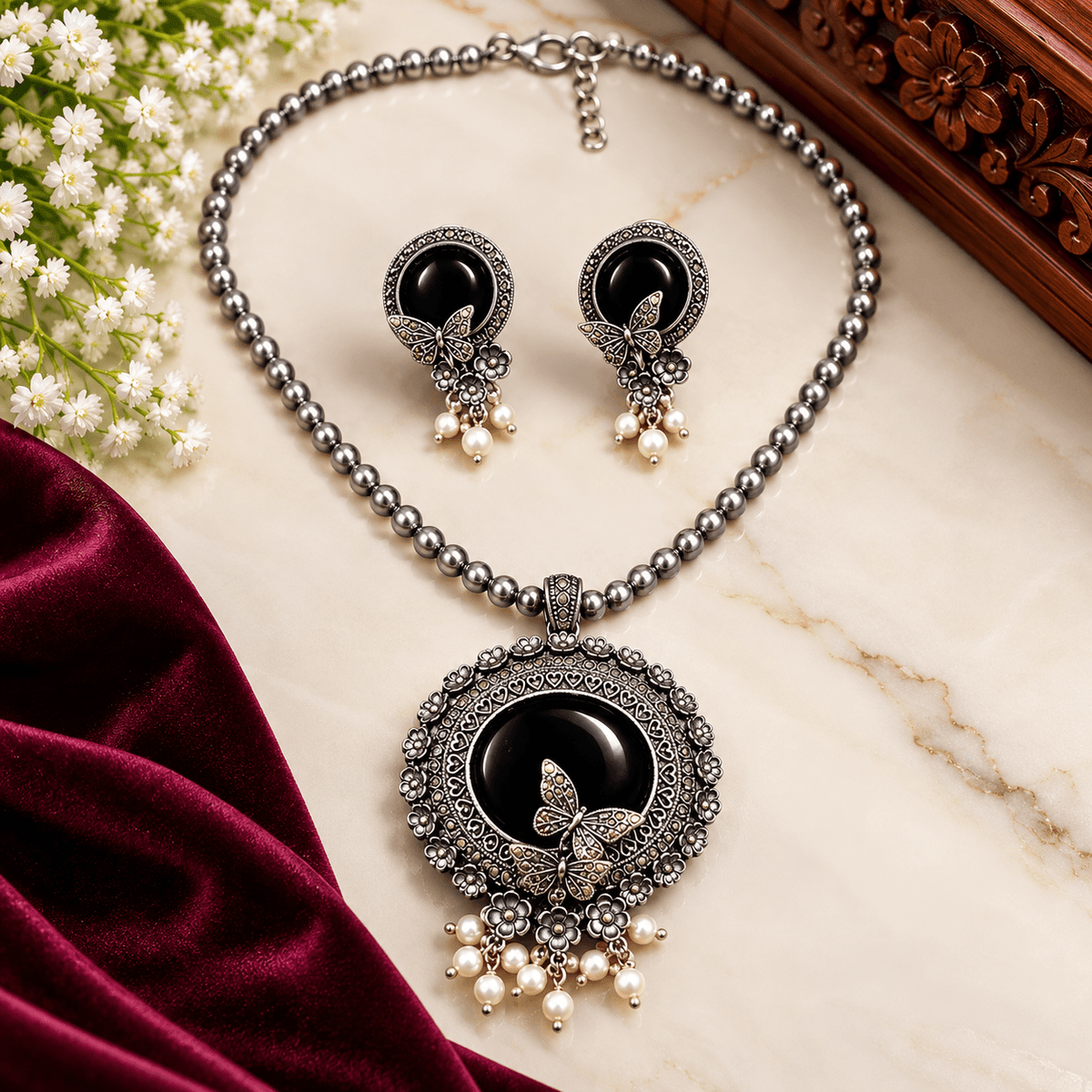 Black stone butterfly pendant necklace with oxidized silver-tone floral detailing, beaded chain, pearl-like drops, and matching earrings