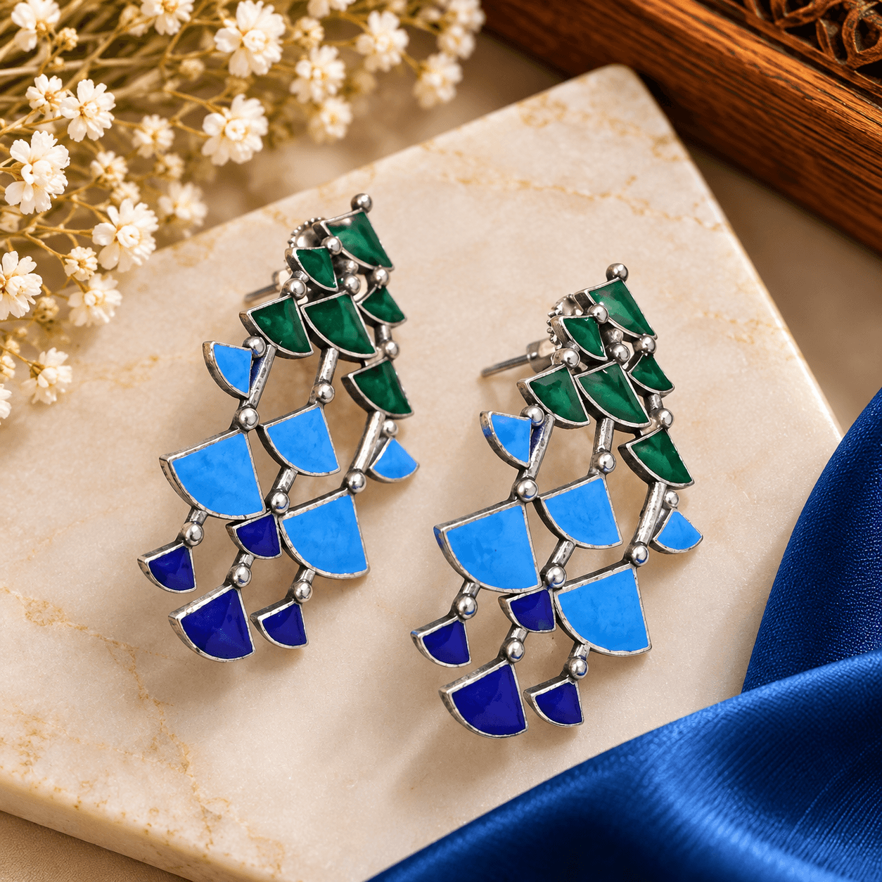 Blue and green geometric Meenakari-style cascade earrings with silver-tone borders and layered mosaic segments