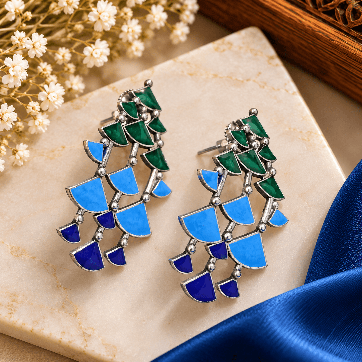 Blue and green geometric Meenakari-style cascade earrings with silver-tone borders and layered mosaic segments