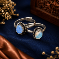 Pair of blue opal-style toe rings with oval stones and oxidized silver-tone decorative settings by The Mirage Fashion.