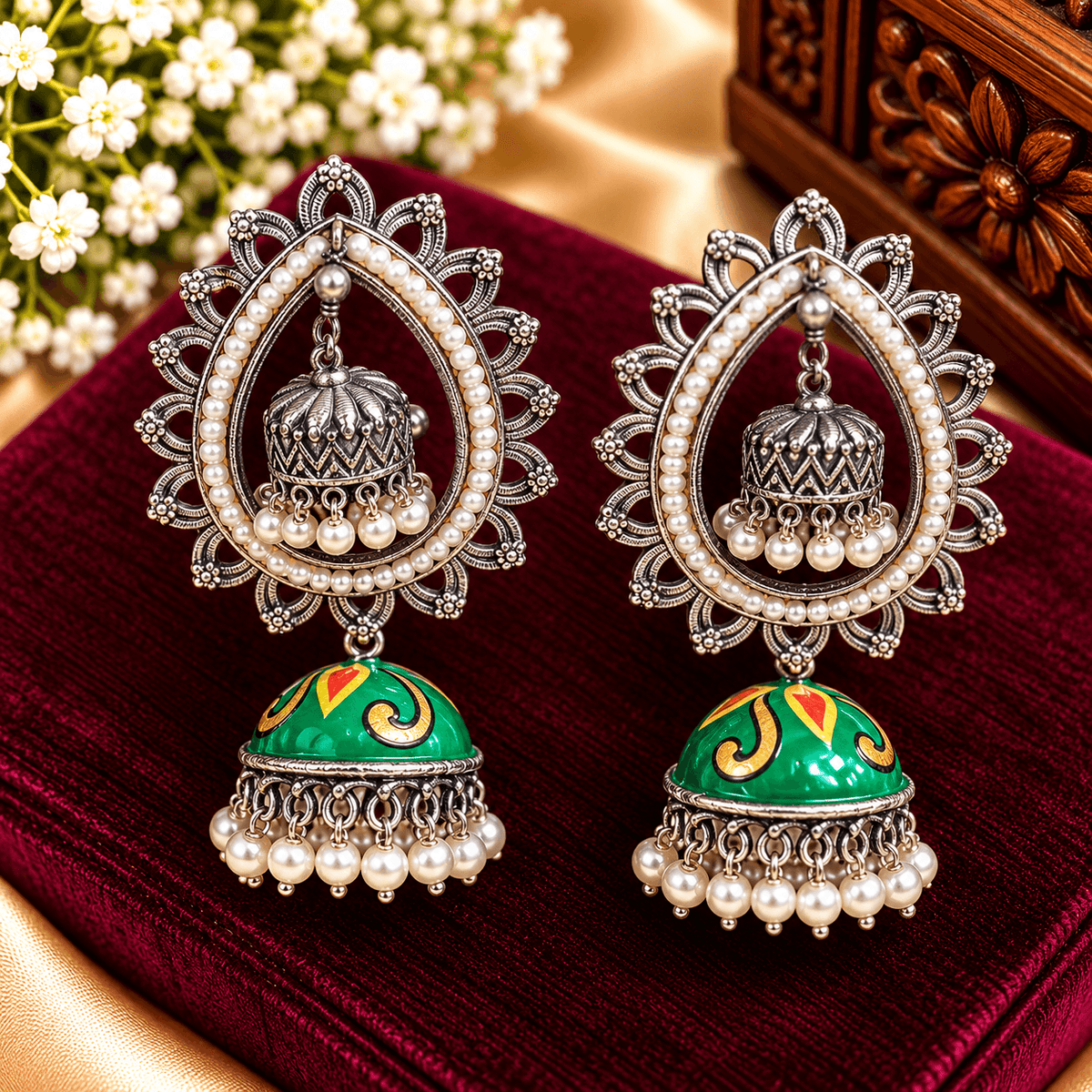 Green enamel jhumka earrings with ornate silver-tone teardrop frames, pearl borders and dangling pearl-style beads