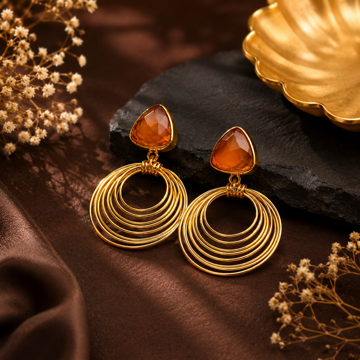 Gold tone geometric drop earrings with orange coloured stone and concentric circles