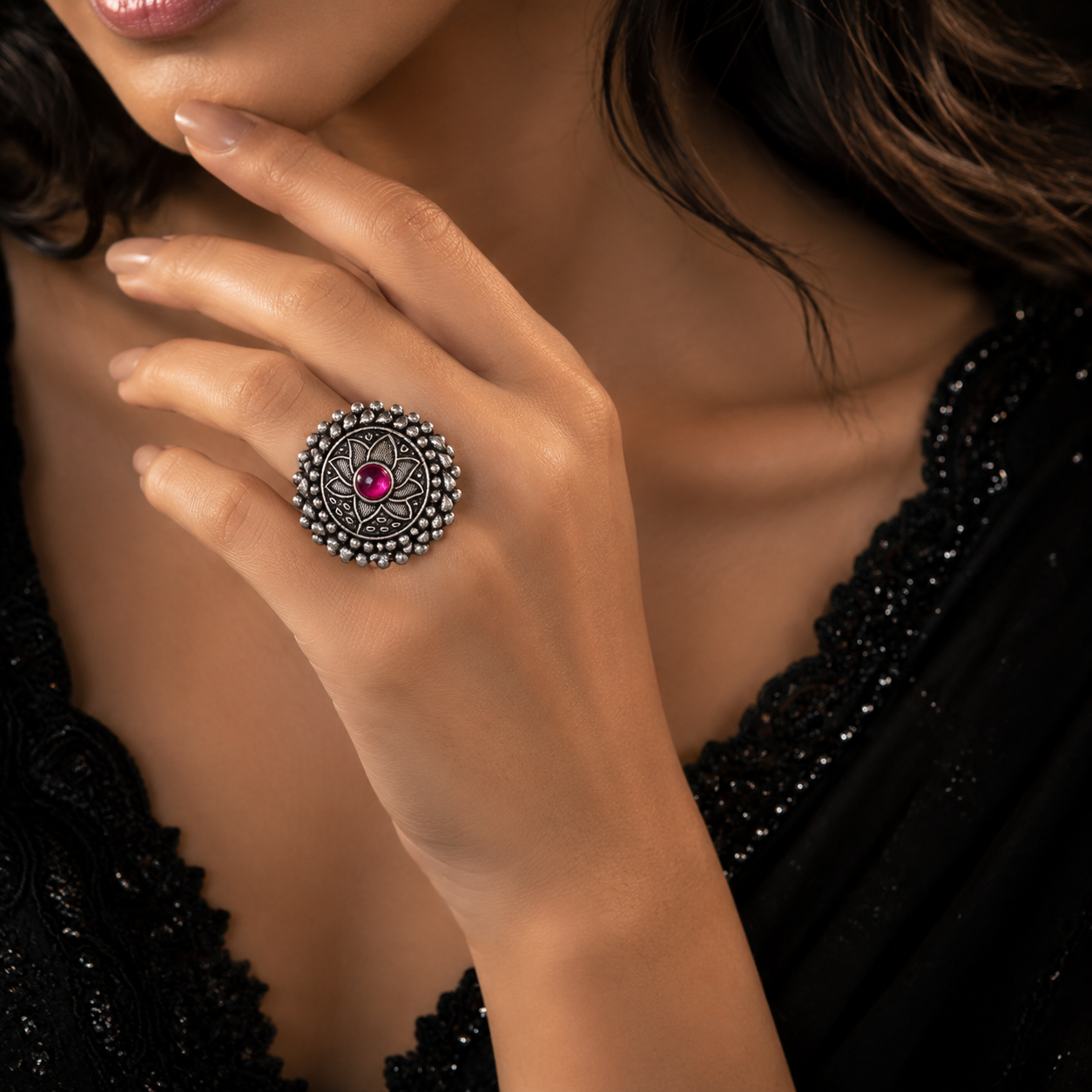 A close-up lifestyle shot of a woman wearing a silver-toned mandala ring with a central pink gemstone on her finger.