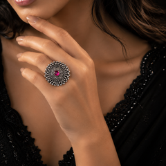 A close-up lifestyle shot of a woman wearing a silver-toned mandala ring with a central pink gemstone on her finger.