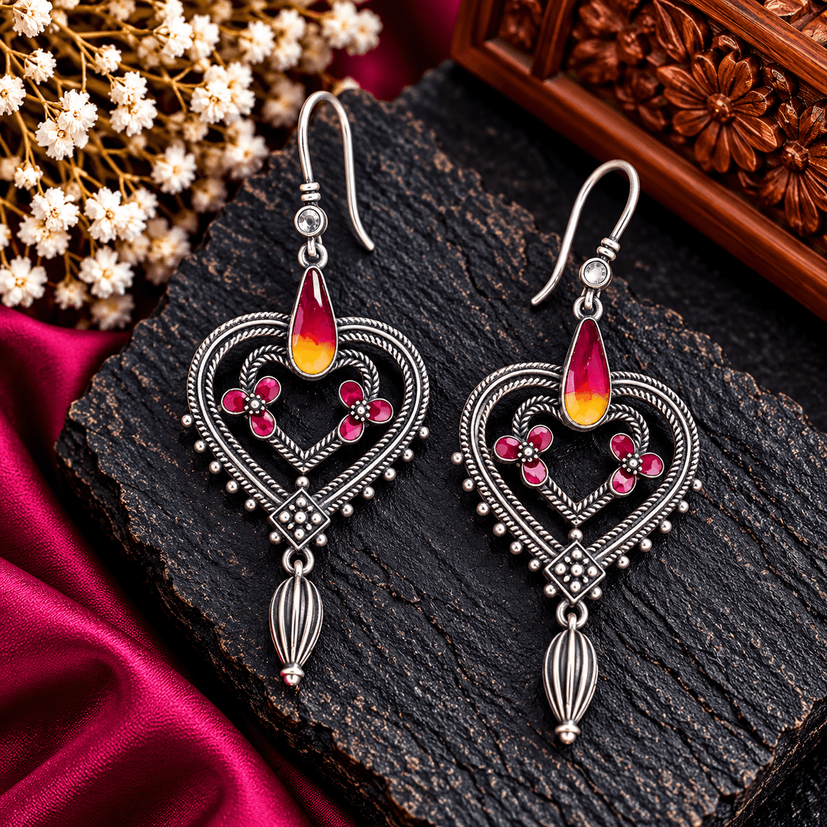 Ruby pink heart-shaped Meenakari earrings with red and yellow enamel accents, floral motifs and antique silver-tone detailing