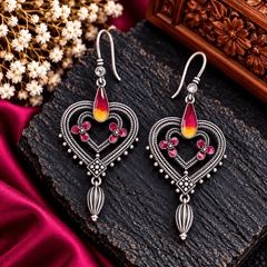 Ruby pink heart-shaped Meenakari earrings with red and yellow enamel accents, floral motifs and antique silver-tone detailing